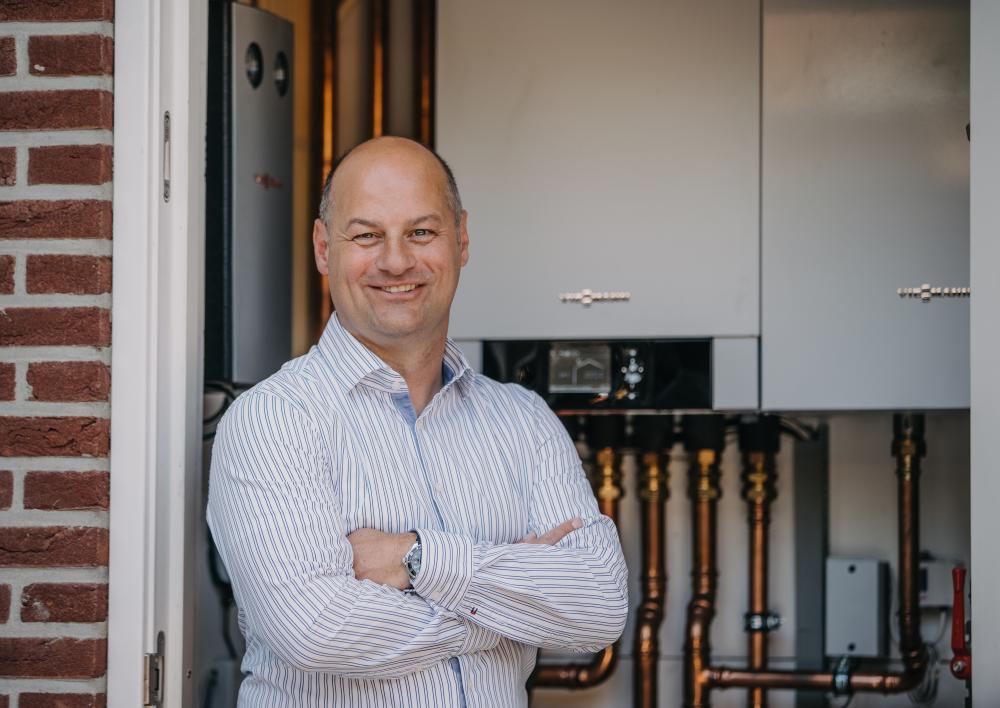 Man poseert met armen over elkaar voor een warmtepomp