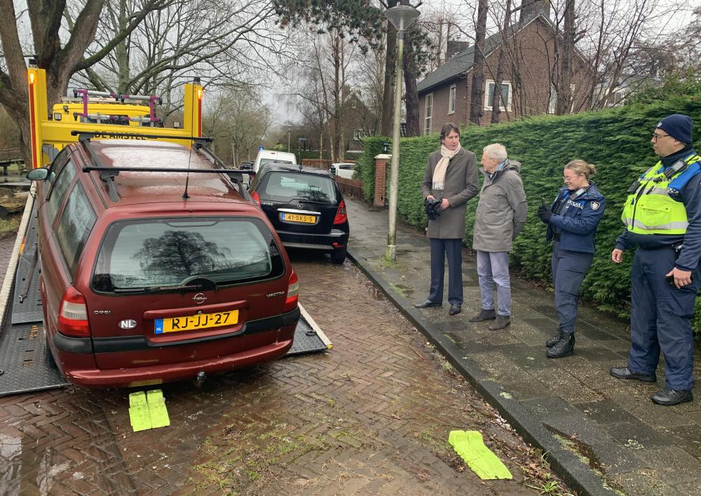 Wethouder Herbert Raat, bewoner John Levie en handhaving bij het wegslepen van een verwaarloosd voertuig op de Emmakade.