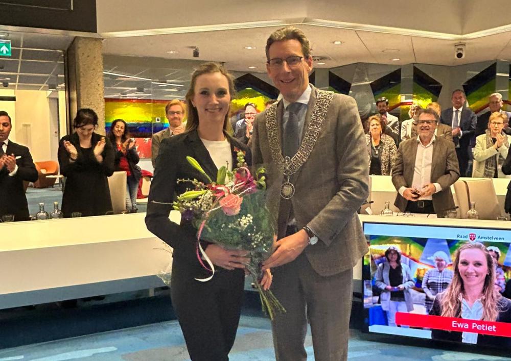Ewa Petiet met de burgemeester haar onderscheiding opgespeld en bloemen