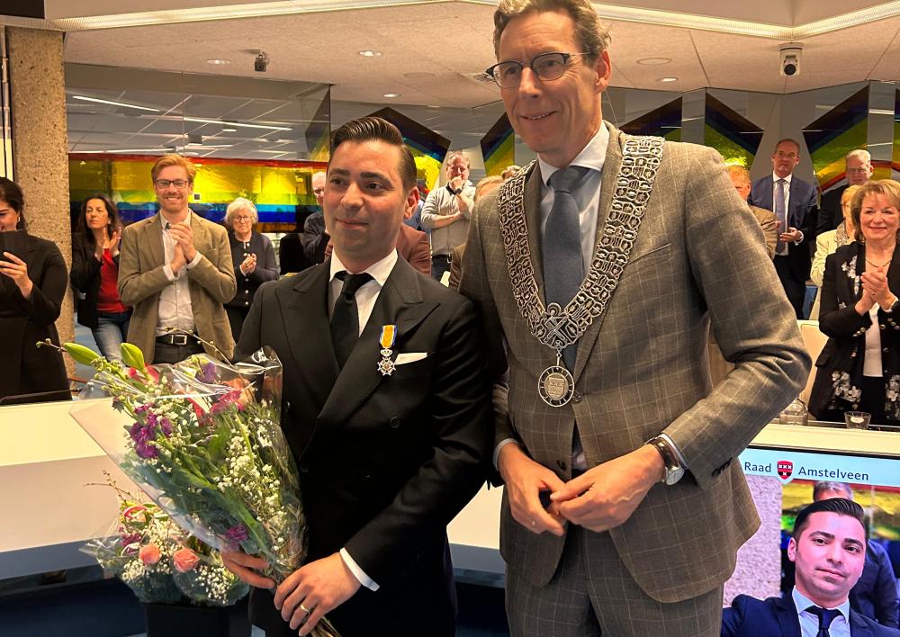 Tawros Aslanjan met onderscheiding opgespeld en bloemen met burgemeester