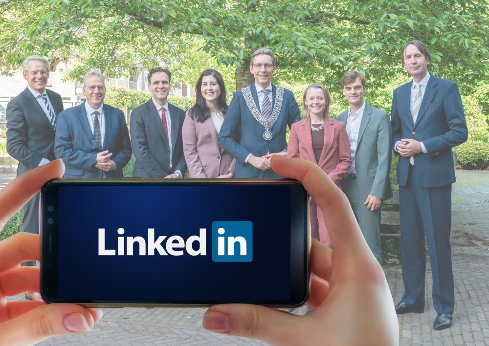 College op de achtergrond, op de voorgrond een mobiele telefoon met LinkedIn in het scherm