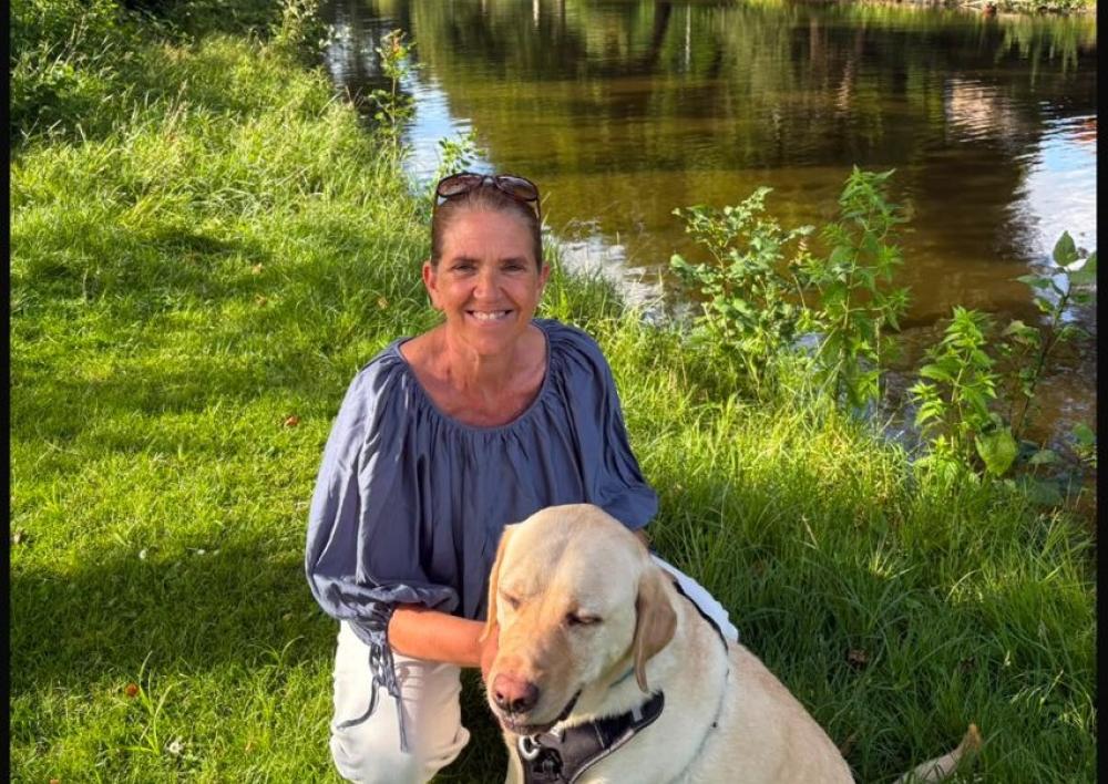 Annet Heuer met hond Cooper in het gras aan het water