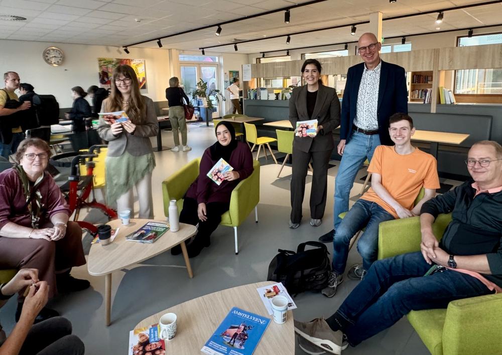 Wethouder Saloua Chaara overhandigt een cadeautje aan een leerkracht van het Keizer Karel College.