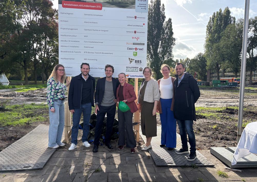 Een groep mensen voor een bord die de start van de bouw onthult. In het midden Wethouder Marijn van Ballegooijen en Wethouder Floor Gordon.