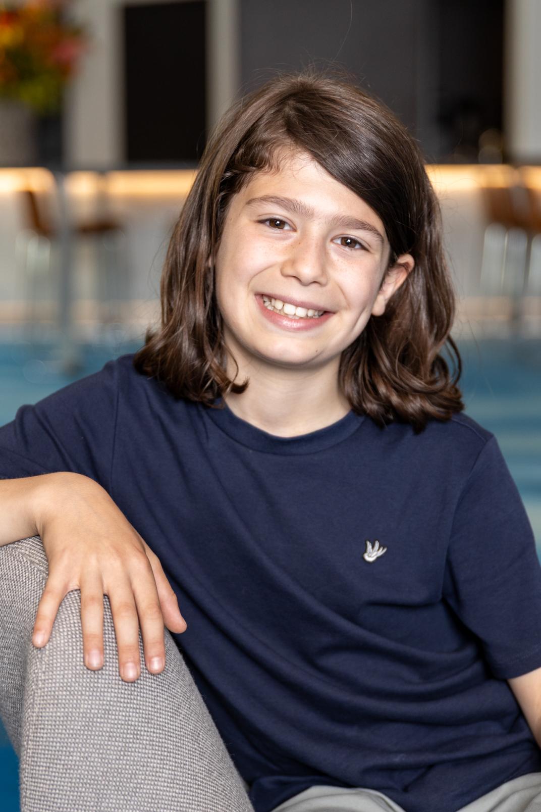 De nieuwe kinderburgemeester Levi zit op de bank en lacht
