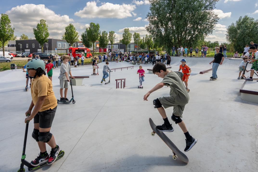 Jongeren op skateboard en steps op de nieuwe skatebaan