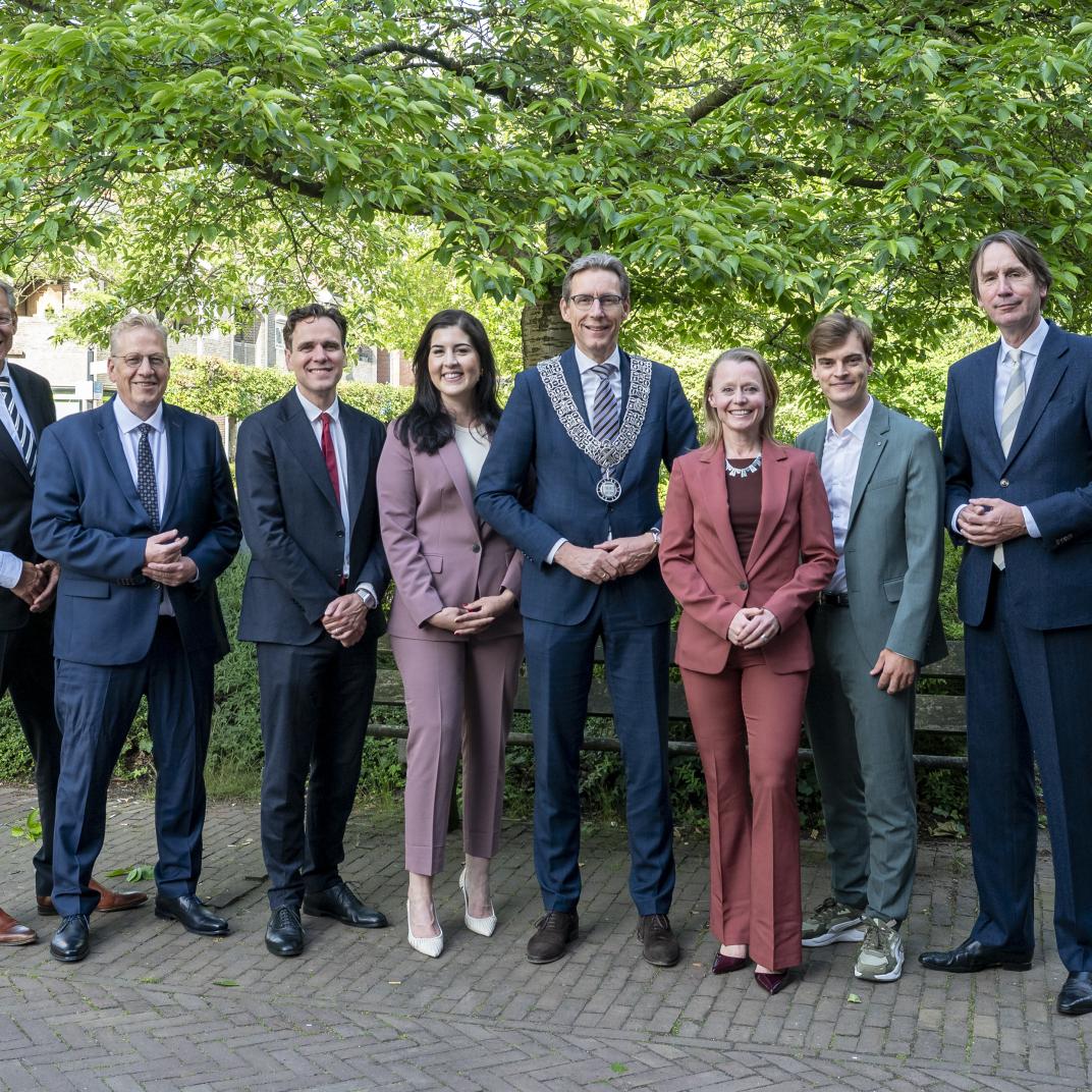 Groepsfoto van de wethouders voor een boom bij het raadhuis